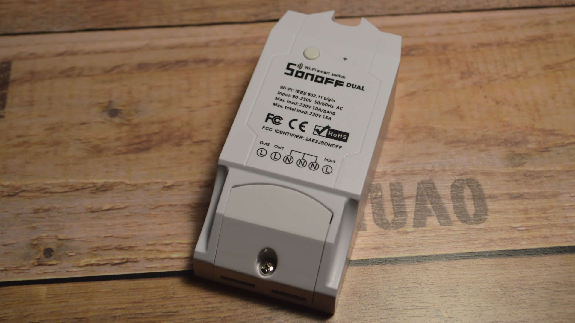 Sonoff Dual on my desk: A white plastic housing with one button and a wiring diagram: Two L out lines, three connected N lines and one input L line.